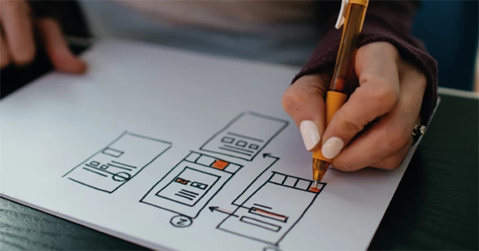 Person zeichnet ein User-Interface-Layout auf Papier, um die Anpassungsfähigkeit der WooCommerce Shopschnittstelle der CTS KG zu demonstrieren.