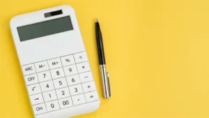 Taschenrechner und Stift auf gelbem Hintergrund, symbolisieren die Kalkulationsarbeit mit der cisKom.BAUKALKULATION der cisKom GmbH.