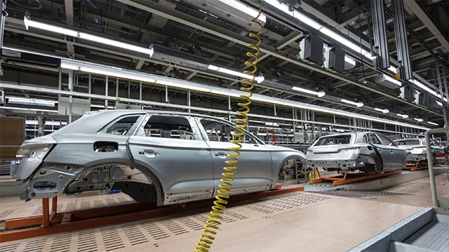 Automobilproduktionslinie mit Karosserien von Fahrzeugen, die die Fertigungseffizienz durch cisKom.AUTOMOTIVE der cisKom GmbH repräsentiert.